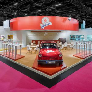 Außenansicht des Halloren Messestands auf der ISM in Köln mit rotem Trabant und Produktpräsentation